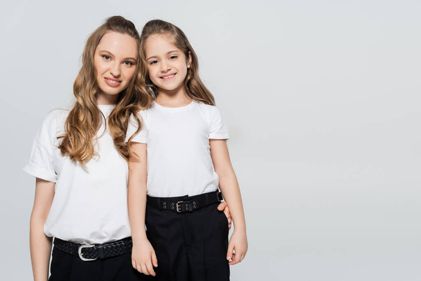 stylish woman with daughter smiling at camera isolated on grey - Photo, Image