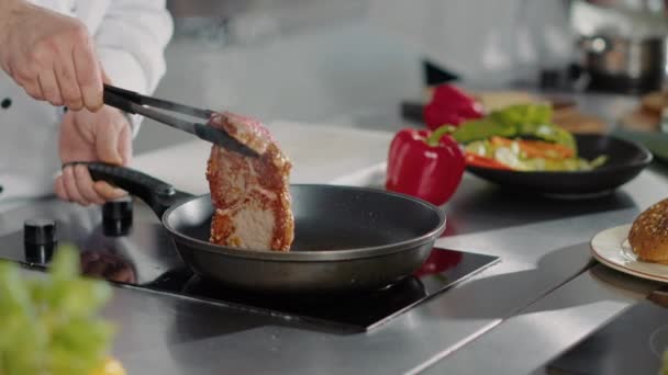 Professionele chef-kok kokend varkensvlees in koekenpan op kachel - Video