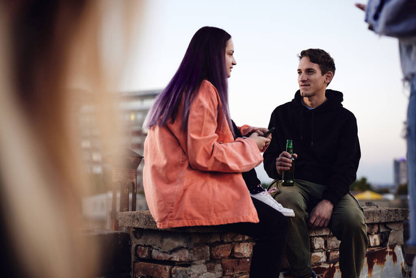 Um adolescente amigo em uma festa no telhado bebendo cerveja e conversando. - Foto, Imagem