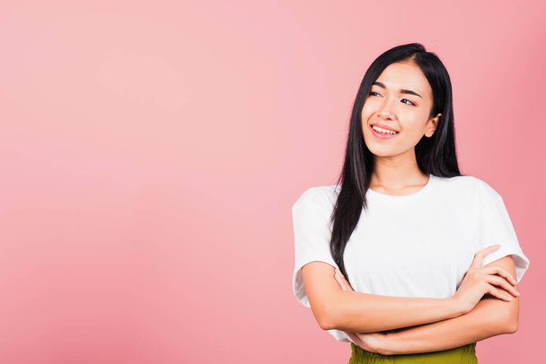 Asian happy portrait beautiful cute young woman standing her smile confidence with crossed arms isolated, studio shot on pink background and copy space, Thai female looking to side away - Photo, image
