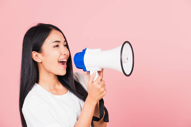 Portrait of happy Asian beautiful young woman teen confident smiling face holding making announcement message shouting screaming in megaphone, studio shot isolated on pink background, with copy space - Фото, зображення