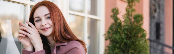 pleased young woman with red hair looking at camera, banner - Foto, Imagem