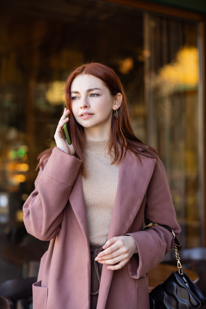 young woman with red hair talking on cellphone outside - Foto, immagini