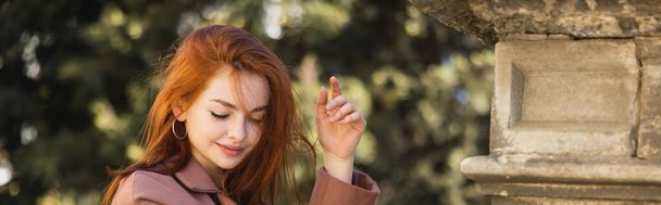 young happy redhead woman in coat posing outside, banner - Foto, imagen