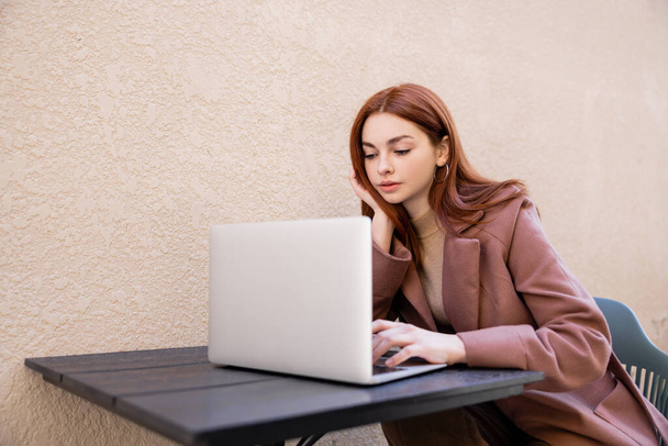 fiatal nő vörös hajú használ laptop kívül - Fotó, kép