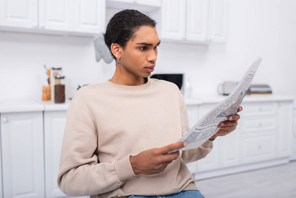 young african american man in beige sweatshirt reading newspaper in morning  - Photo, Image