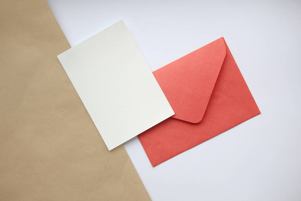 Postcard mockup vertical, on white and brown background red closed envelope and white sheet - Photo, Image
