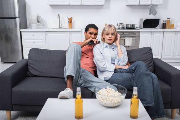 young multiethnic couple watching scary movie in living room - Foto, Imagem