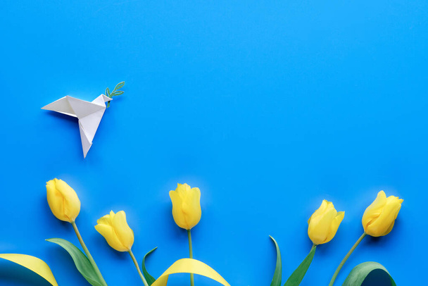 Dove of peace, paper origami. Peace to Ukraine. Yellow tulips, flowers, on blue background. Copy-space, place for text. Top view, flat lay, concept background. - Φωτογραφία, εικόνα