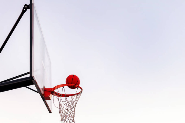 ball entering in a basketball hoop with the sky in the background, concept of urban sport outdoors, copy space for text - Foto, afbeelding
