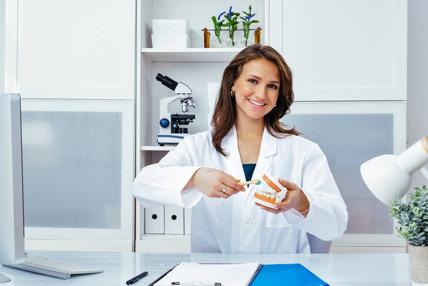χαμογελαστή γυναίκα γιατρός δείχνει ανθρώπινα σαγόνια και τα δόντια mockup  - Φωτογραφία, εικόνα