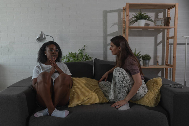 Two young college lesbian homosexual couple in relationship women argue in their home in the dark without electricity about spending money for rent on party and night out with huge bills and credit - Photo, Image