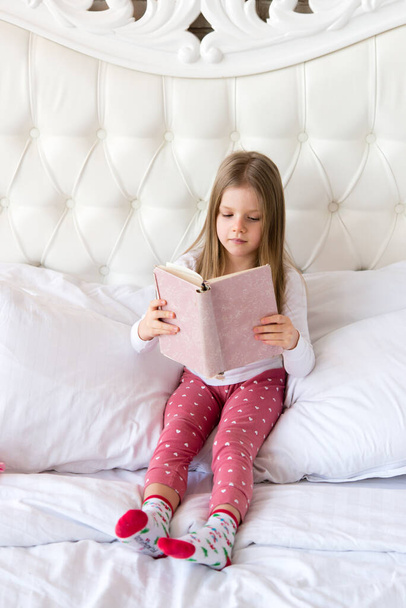 little girl lies in bed and reads a book. - Fotó, kép