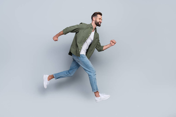 Full length body size view of attractive cheerful active guy jumping running isolated over grey pastel color background - Foto, Bild