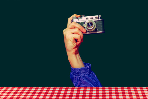 Concept of pop art photography. Using retro gadgets. Human hand holding photo camera isolated on green background. Vintage fashion style. Concept of nostalgia - Photo, Image