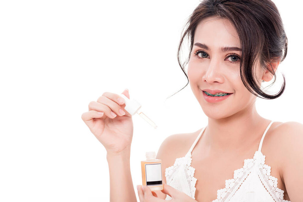 Asian young beautiful woman smiling she's holding bottle serum hair or skin care near face for present product isolated on over white background, Beauty salon concept - 写真・画像