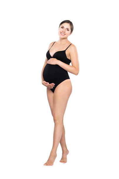 Young pregnant woman in black swimsuit. Girl expecting a baby and touching her belly isolated on white background. - Fotografie, Obrázek