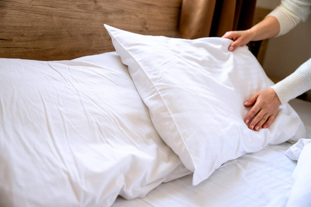 Vrouw maakt het bed op in de slaapkamer. Schoonmaakster Schoonmaken rommelig hotel bed kussen en dekbed, verschonen lakens met schone Selectieve focus. Kopieerruimte - Foto, afbeelding