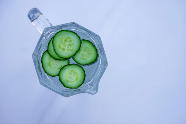 Fresh Cucumber infused Water in the glass jug on grey background. Detox and refreshment drink. Above close up view with copy space - Photo, Image