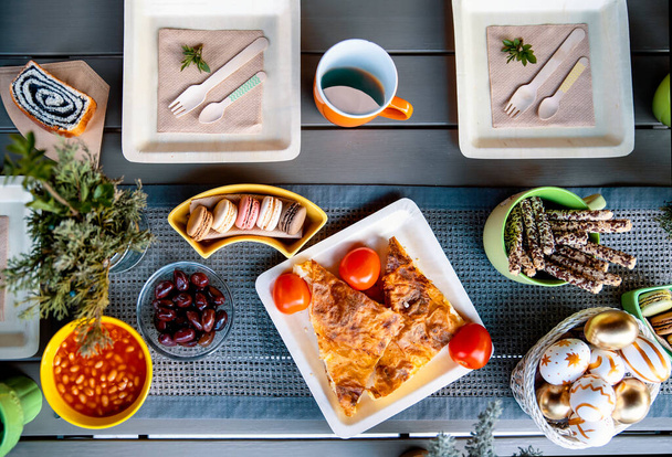 Repas de brunch de Pâques dans des assiettes en bambou biodégradables servant sur une table de balcon. Variété de nourriture pour appartement de petit déjeuner de vacances se trouvait d'en haut - Photo, image