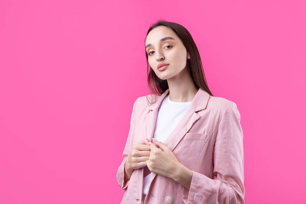 Портрет красивой молодой женщины в розовой куртке, мыслящей изолированно на красном фоне - Фото, изображение