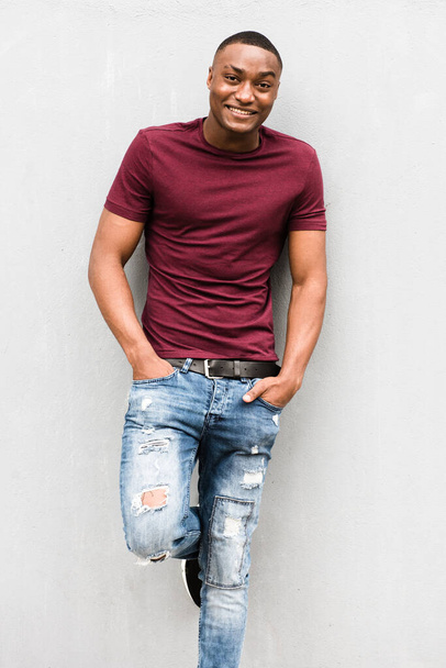 Ritratto di giovane afroamericano sorridente in posa su sfondo grigio - Foto, immagini