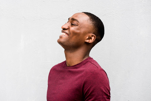 Retrato de cerca del perfil de un joven afroamericano feliz riendo sobre un fondo gris  - Foto, imagen