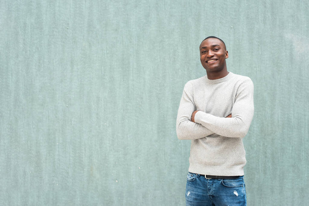 Πορτρέτο του χαμογελαστού Αφροαμερικανού με τα χέρια σταυρωμένα σε πράσινο φόντο  - Φωτογραφία, εικόνα