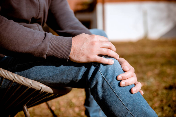 Man hands holding painful knee outdoor. Male having sore pain in meniscus - Photo, image