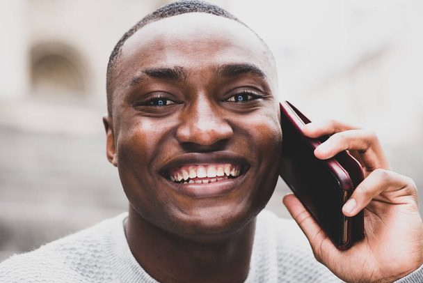 Close up portret szczęśliwego Afroamerykanina rozmawiający ze smartfonem - Zdjęcie, obraz