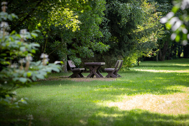 two wooden benches and a table in a park - Foto, Bild