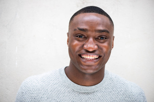 Close up portret szczęśliwego Afroamerykanina uśmiecha się przez białą ścianę - Zdjęcie, obraz