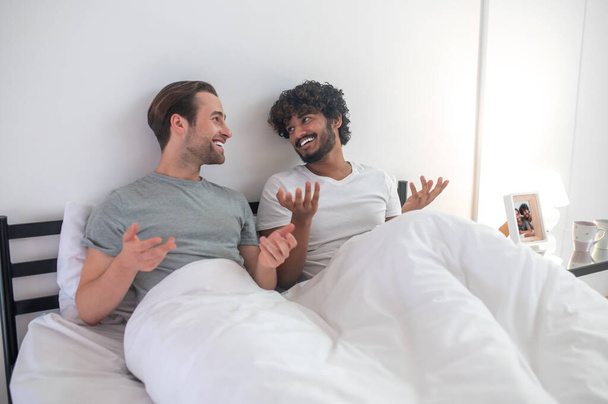 Gay couple talking to each other in their bedroom - Fotó, kép