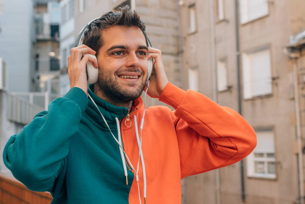 fiatal férfi fejhallgatóval a város utcájában szabadban - Fotó, kép