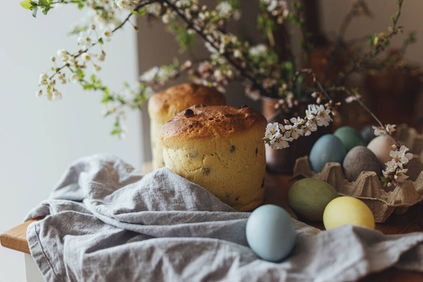 Szczęśliwej Wielkanocy! Domowej roboty chleb wielkanocny, naturalne barwione jaja i wiosenny kwiat na rustykalnym stole w pokoju. Świeżo upieczone ciasto wielkanocne, tradycyjna ukraińska bułka - Zdjęcie, obraz