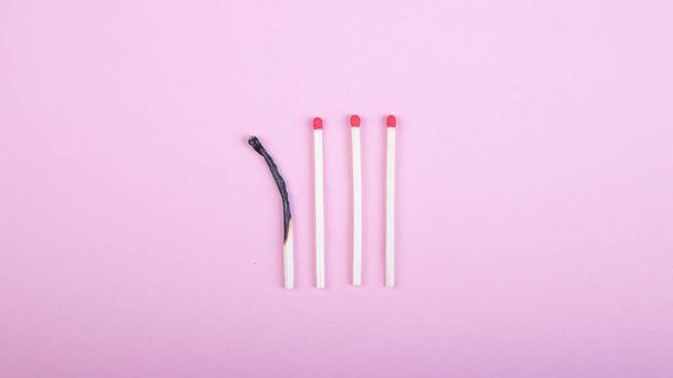 four match sticks, one burned on pink background - Zdjęcie, obraz