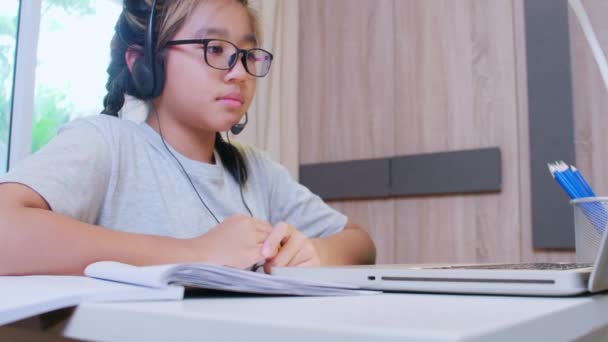 4K Opi kotiin käsite. Aasian tyttö opiskelijat oppivat virtuaalinen internet online-luokan etäkokouksen vuoksi covid-19 pandemia. Tyttö opiskelija oppimisen verkossa kannettavan kotona - Materiaali, video