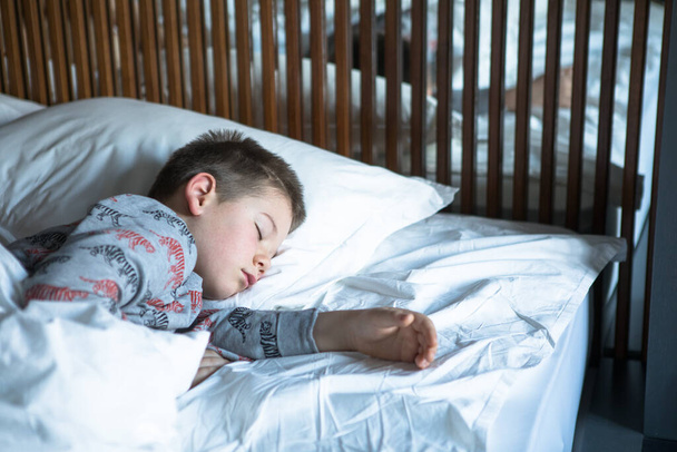 Yatakta uyuyan sevimli küçük çocuk. Tatlı çocuk evde huzur içinde rüya görüyor.. - Fotoğraf, Görsel