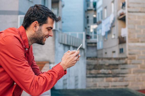 человек с мобильным телефоном на улице на террасе или балконе - Фото, изображение
