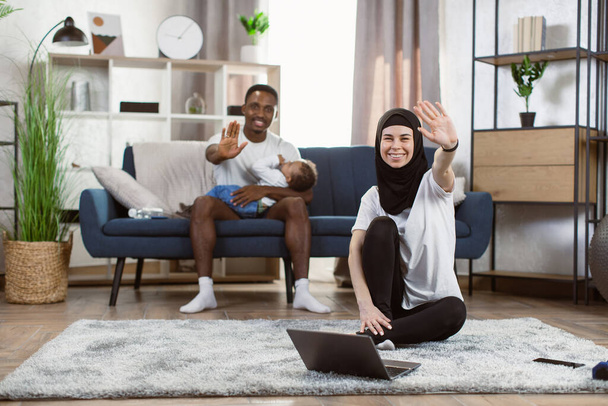 Arabic girl in hijab practicing online yoga, excersising in living room - Фото, изображение