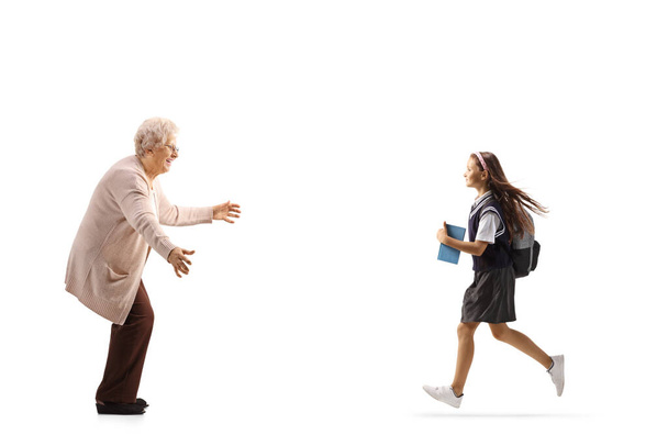 Profilbild in voller Länge von einem Schulmädchen, das zur Großmutter rennt, um sie isoliert auf weißem Hintergrund zu umarmen - Foto, Bild