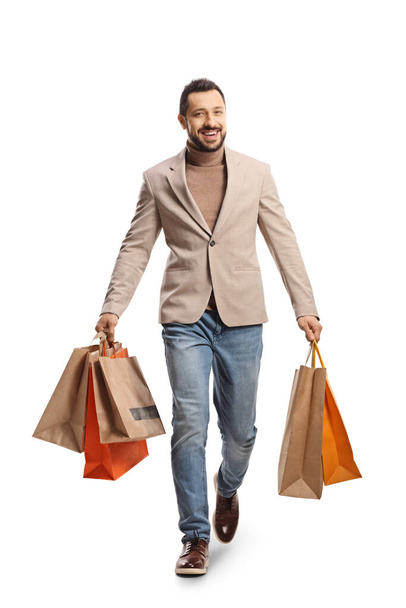 Full length portrait of a man carrying shopping bags and walking towards camera isolated on white background - Fotografie, Obrázek
