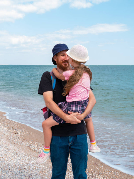 Mutlu aile babası kızı deniz manzarasında sarılıyor. Sakallı baba, elinde çocukla birlikte deniz suyuna bakarken eğleniyor. Otantik yaşam tarzı gerçek insanlar. Seyahat Babalar Günü Güney Ukrayna - Fotoğraf, Görsel