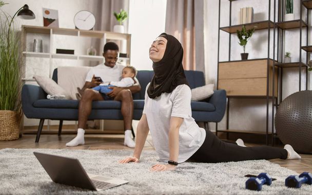 Portrait of fit arabic smilling woman doing gymnastics on mat in the living room - Фото, зображення