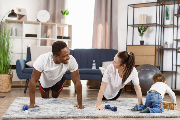 Young attractive family african man and woman doing push up exercises workout at home - Φωτογραφία, εικόνα