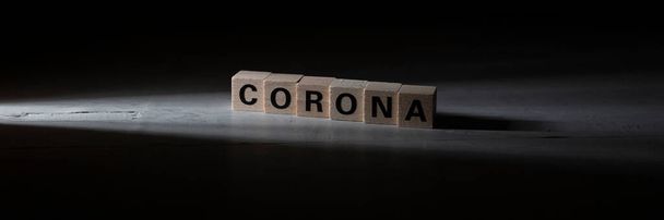 bloques de madera que construyen la palabra corona, fondo negro - Foto, Imagen