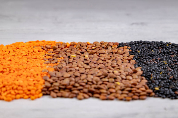 brown, red and black lentils on a wooden board - Фото, изображение