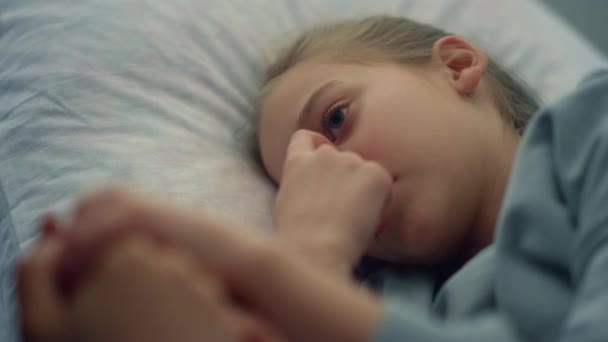 Aranyos lány fekszik kórházi ágykép. Anya gyengéden fogja a gyermek kezét közelről. - Felvétel, videó