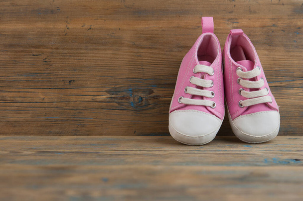 Chaussures de sport pour bébés sur sol en bois. Baskets de petite taille pour enfants, chaussons en toile vue rapprochée. Espace, modèle d'invitation de carte - Photo, image
