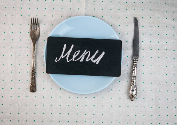 Restaurant menu ontwerp. Restaurant menu met leeg bord en bestek, op bolletjestafel met kleurrijk servet. Bovenaanzicht met kopieerruimte voor tekst - Foto, afbeelding